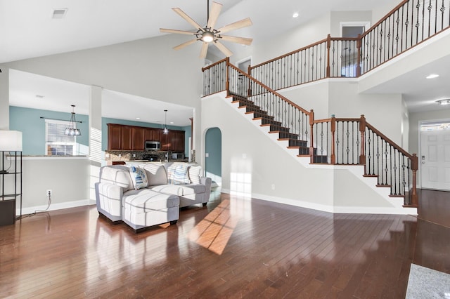 living area with stairs, a high ceiling, dark wood-style floors, and baseboards