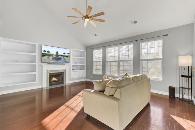 living room featuring dark wood-type flooring, plenty of natural light, visible vents, and built in shelves