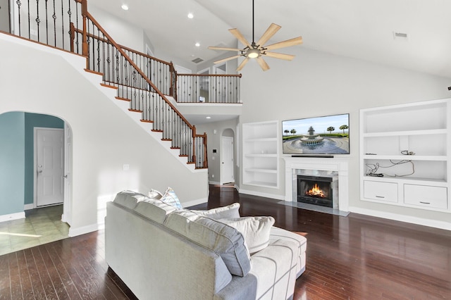 living area with arched walkways, built in features, a fireplace, and wood-type flooring