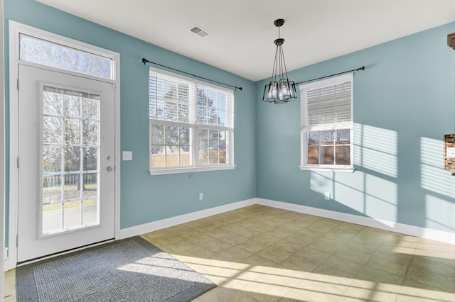 unfurnished dining area featuring visible vents, baseboards, a healthy amount of sunlight, and an inviting chandelier