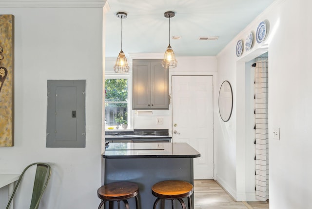 kitchen with pendant lighting, electric panel, crown molding, light hardwood / wood-style flooring, and a kitchen bar