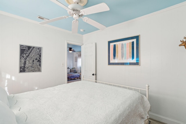 bedroom with ceiling fan, wooden walls, and ornamental molding