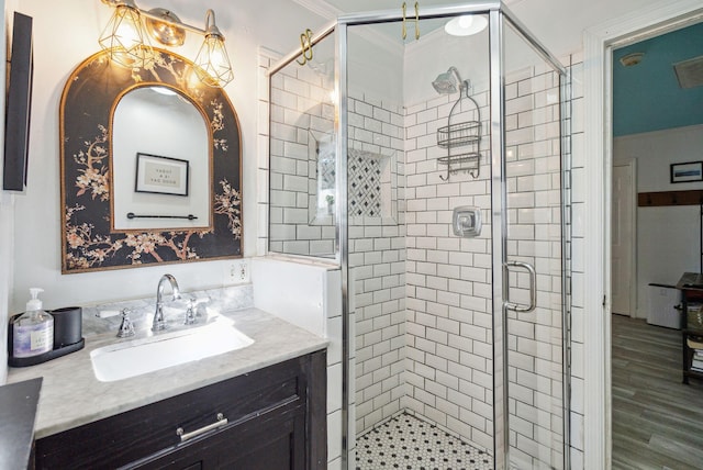 bathroom featuring crown molding, vanity, wood-type flooring, and an enclosed shower