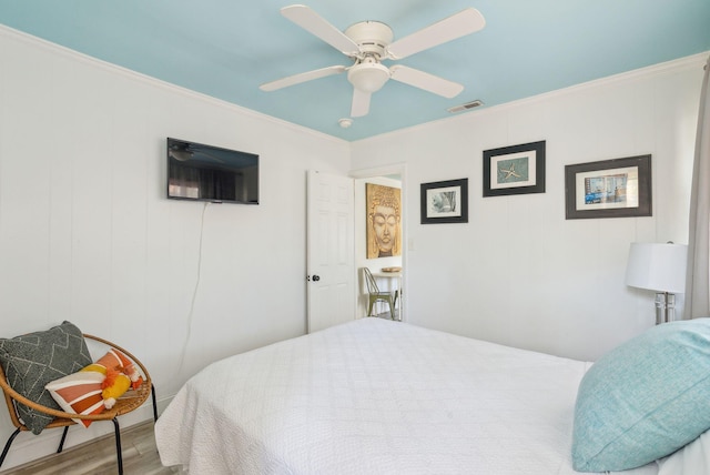 bedroom featuring hardwood / wood-style flooring, ceiling fan, and ornamental molding