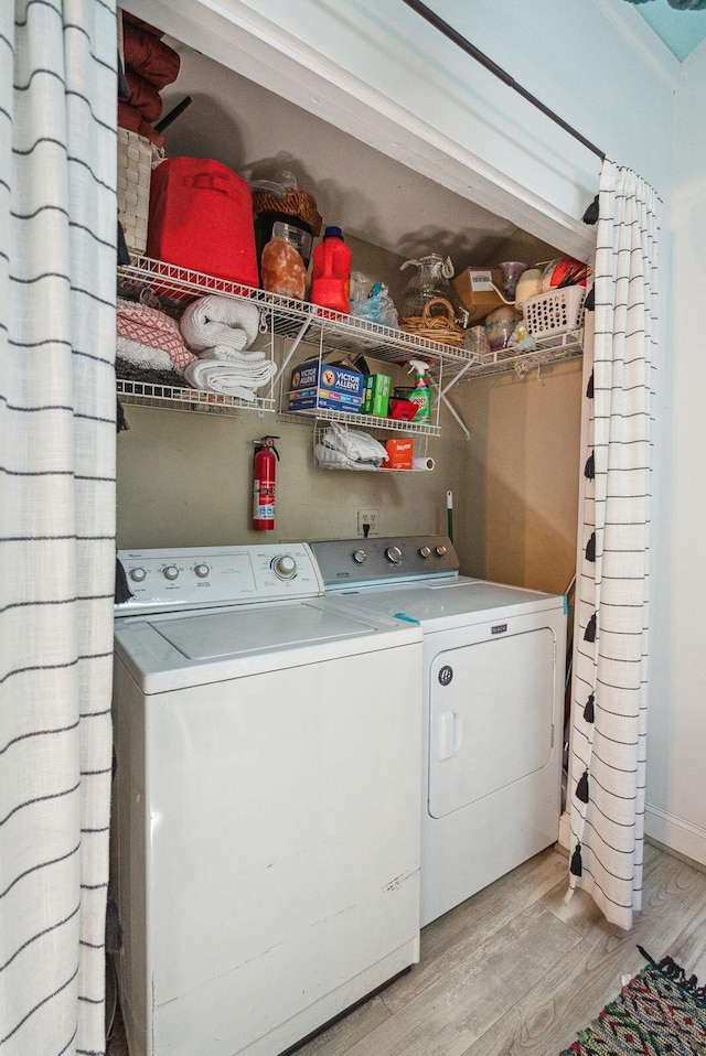 clothes washing area with light hardwood / wood-style flooring and washer and dryer