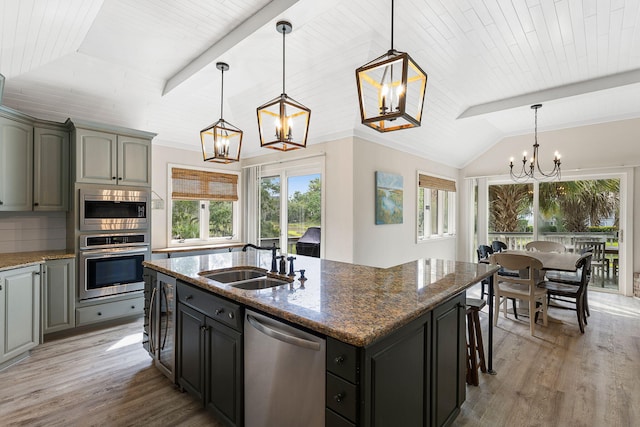 kitchen with vaulted ceiling with beams, stainless steel appliances, light wood-style floors, a chandelier, and a sink