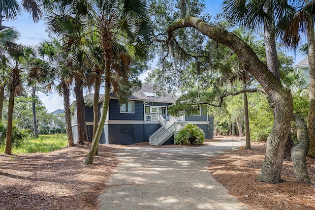 coastal home featuring driveway and stairway