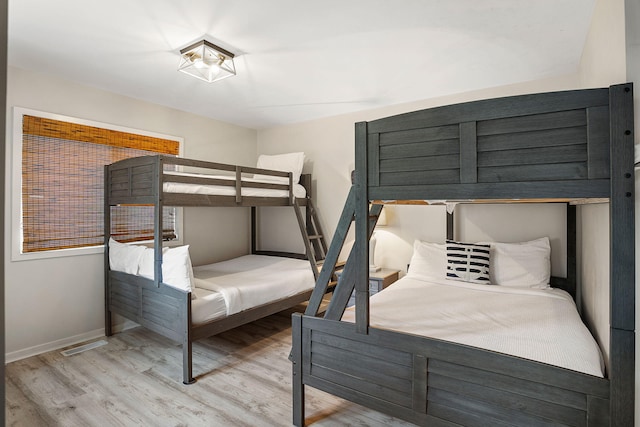 bedroom with visible vents, baseboards, and wood finished floors