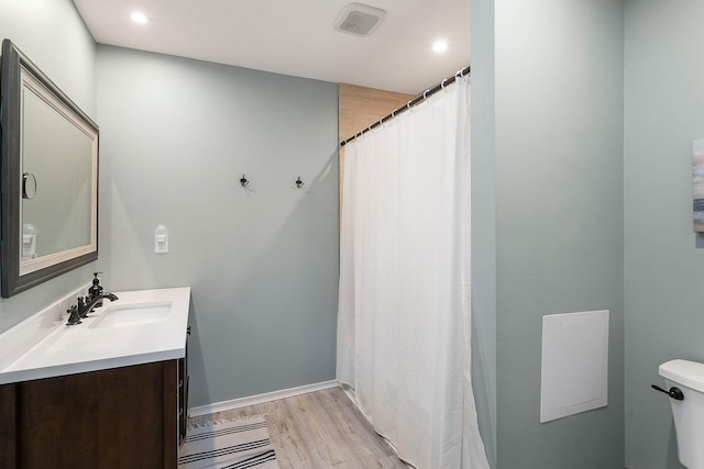 bathroom with visible vents, a shower with shower curtain, toilet, wood finished floors, and vanity