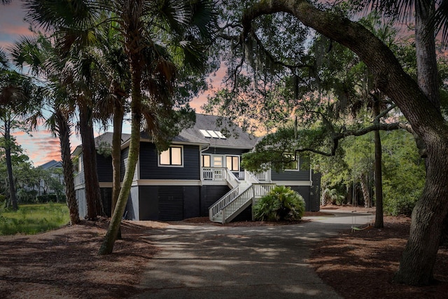 raised beach house featuring driveway and stairway