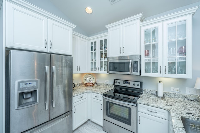 kitchen with white cabinets, stainless steel appliances, and vaulted ceiling