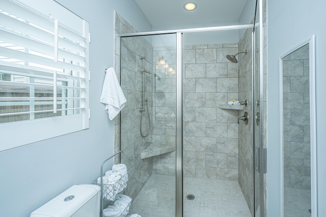 bathroom featuring a shower with shower door and toilet