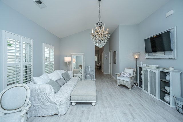 living room featuring a notable chandelier, lofted ceiling, and light hardwood / wood-style floors