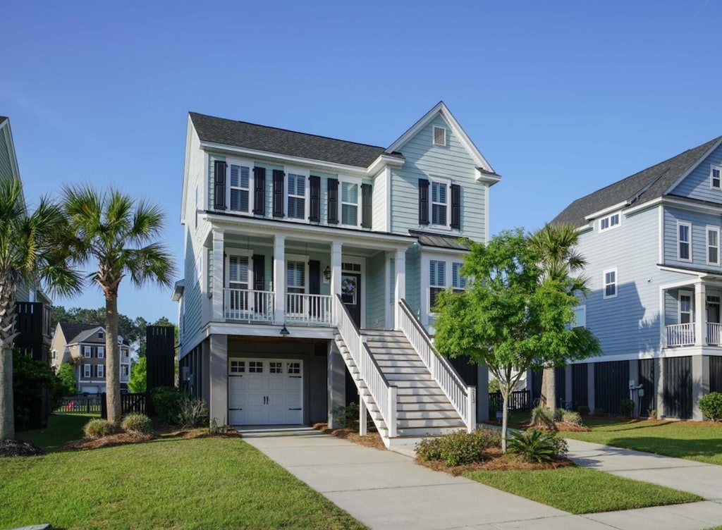 view of front of property featuring covered porch, a garage, and a front lawn