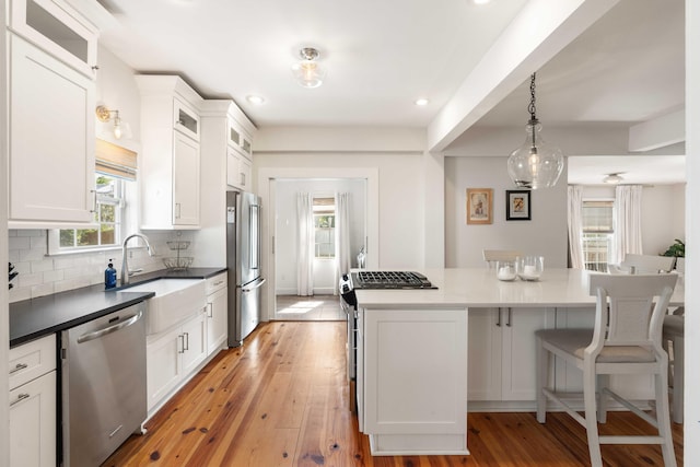 814 Rutledge Ave, Charleston, SC 29403 - kitchen with appliances with stainless steel finishes, a kitchen island, light wood finished floors, white cabinetry, and tasteful backsplash