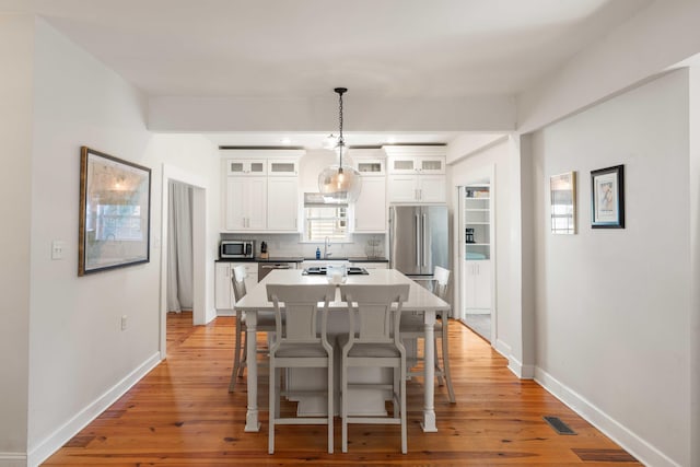 814 Rutledge Ave, Charleston, SC 29403 - kitchen with stainless steel appliances, tasteful backsplash, a center island, a breakfast bar, and white cabinets