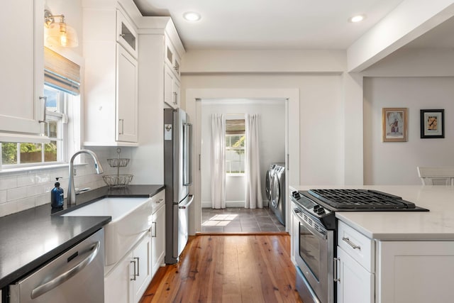 814 Rutledge Ave, Charleston, SC 29403 - kitchen featuring stainless steel appliances, washer and dryer, a sink, backsplash, and white cabinetry