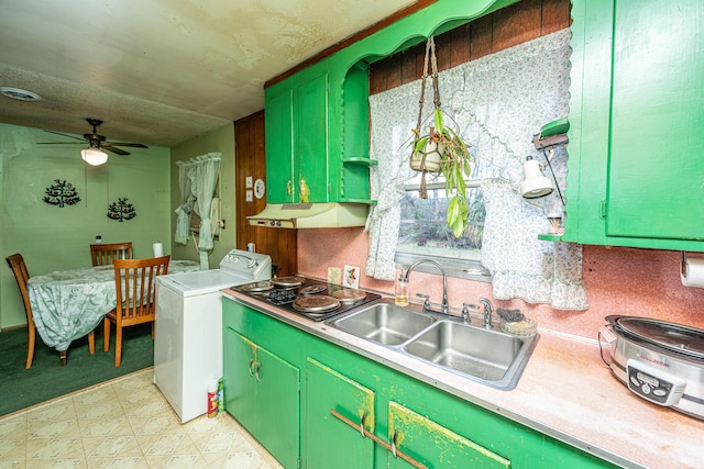 kitchen featuring under cabinet range hood, a sink, light countertops, washer / clothes dryer, and green cabinetry