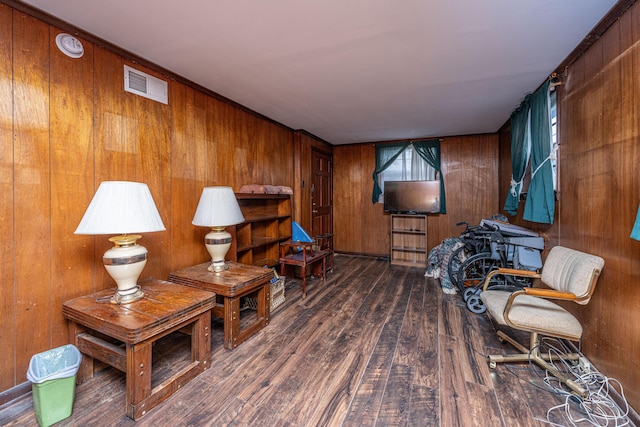 sitting room featuring dark wood-type flooring, visible vents, and wooden walls