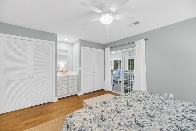 bedroom featuring visible vents, two closets, wood finished floors, and a ceiling fan