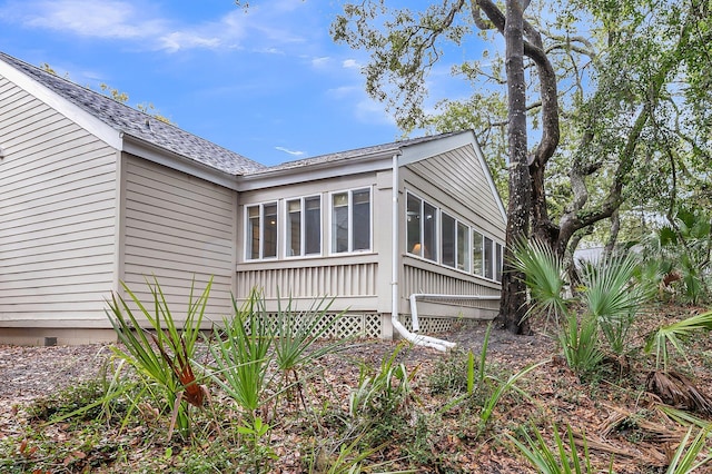 view of side of home featuring roof with shingles and a sunroom