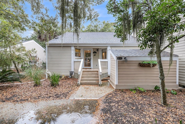 ranch-style house featuring roof with shingles and a porch