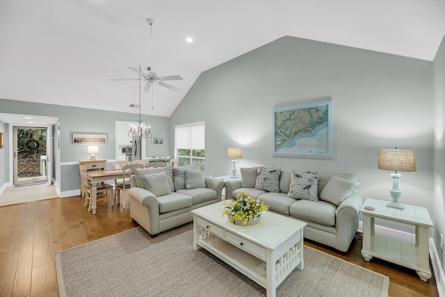 living area with baseboards, recessed lighting, ceiling fan with notable chandelier, wood finished floors, and high vaulted ceiling