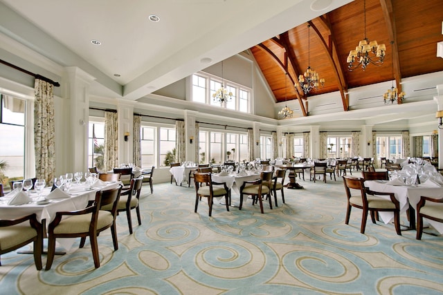 carpeted dining room featuring wooden ceiling, a notable chandelier, a healthy amount of sunlight, and high vaulted ceiling