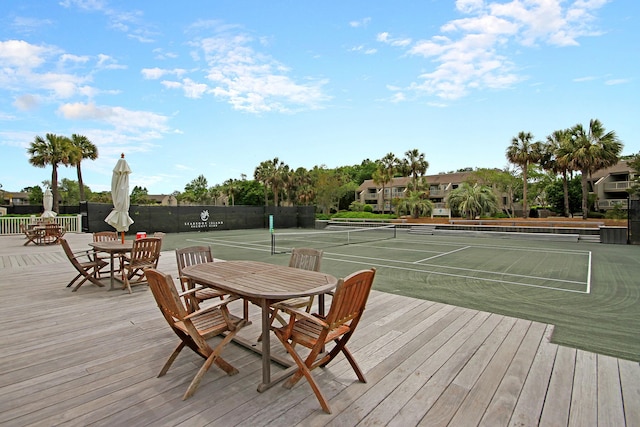 wooden terrace featuring a tennis court and fence