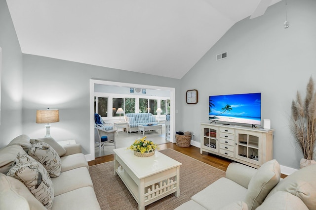 living room featuring visible vents, baseboards, high vaulted ceiling, and wood finished floors