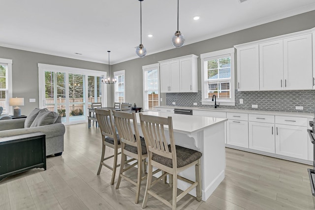 kitchen with white cabinets, a breakfast bar area, a center island, sink, and decorative light fixtures