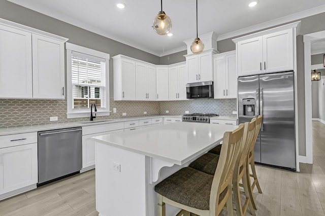 kitchen with decorative light fixtures, stainless steel appliances, white cabinets, and a center island