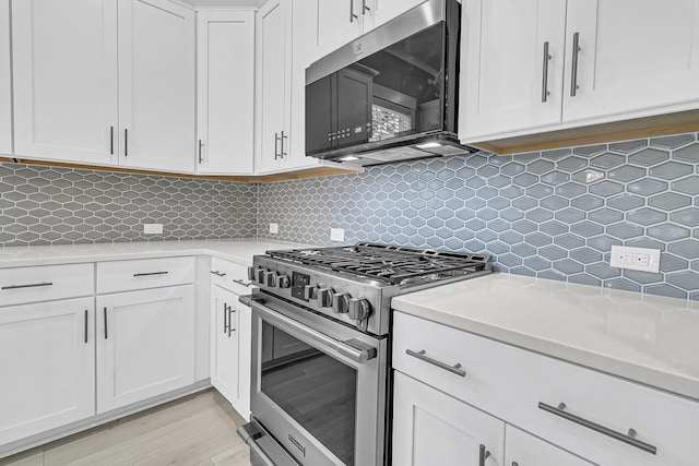 kitchen with white cabinetry, light hardwood / wood-style flooring, decorative backsplash, light stone countertops, and gas range