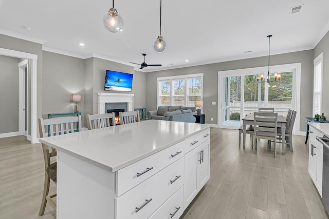 kitchen with hanging light fixtures, white cabinetry, a kitchen island, and a kitchen breakfast bar