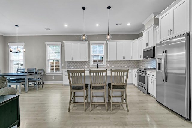 kitchen featuring hanging light fixtures, a kitchen island, white cabinets, appliances with stainless steel finishes, and a kitchen breakfast bar