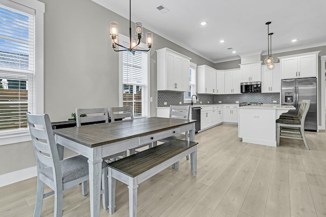 dining room featuring a notable chandelier, crown molding, light hardwood / wood-style floors, and sink