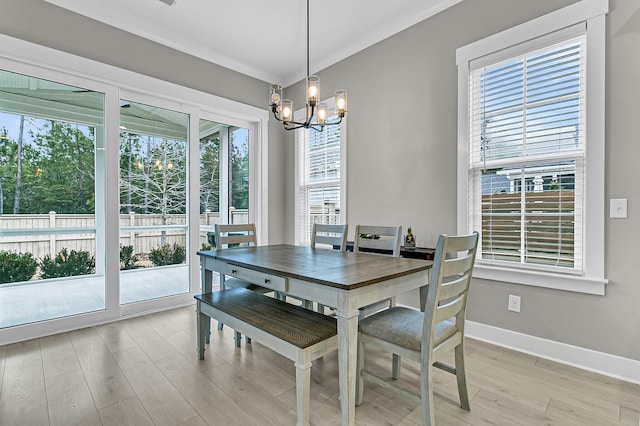 dining space featuring ornamental molding, a notable chandelier, and light hardwood / wood-style flooring