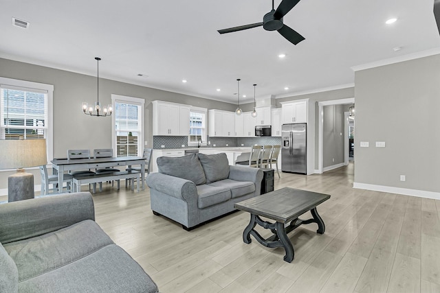 living room featuring ceiling fan with notable chandelier, sink, ornamental molding, and light hardwood / wood-style floors