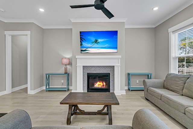 living room with a fireplace, ceiling fan, light hardwood / wood-style floors, and ornamental molding