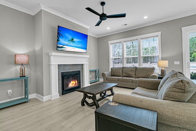 living room with light hardwood / wood-style floors, ceiling fan, a healthy amount of sunlight, and a brick fireplace