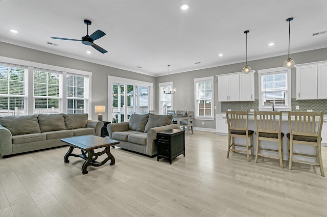 living room featuring ceiling fan with notable chandelier, light hardwood / wood-style floors, and a wealth of natural light