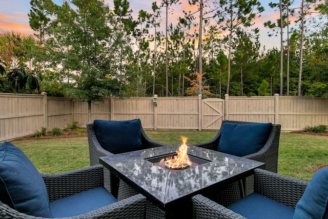 patio terrace at dusk featuring a fire pit and a yard