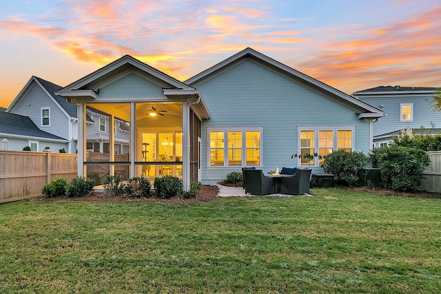 back house at dusk with ceiling fan, a yard, and an outdoor hangout area