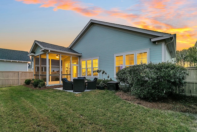 back house at dusk featuring cooling unit, a patio, a yard, and a sunroom