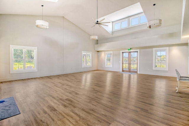 unfurnished living room featuring a towering ceiling, ceiling fan, and hardwood / wood-style floors