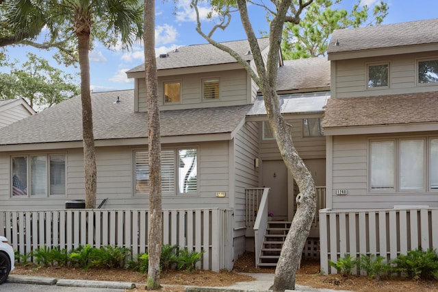 exterior space with fence and a shingled roof