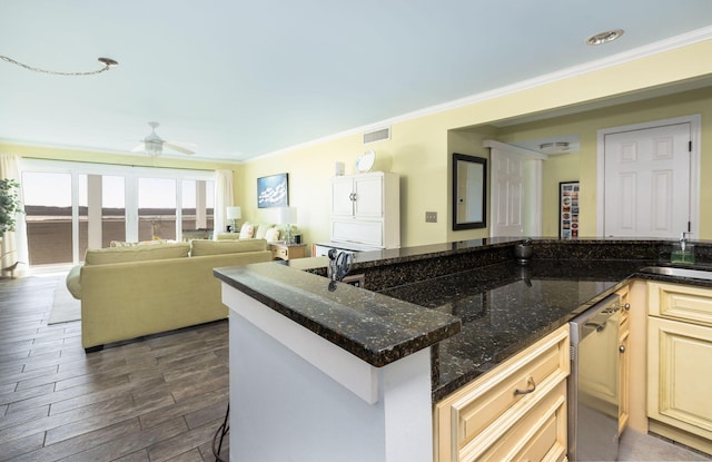 kitchen featuring visible vents, dark wood finished floors, dark stone counters, ornamental molding, and a ceiling fan