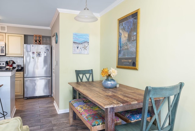 dining space with dark wood finished floors, visible vents, baseboards, and ornamental molding