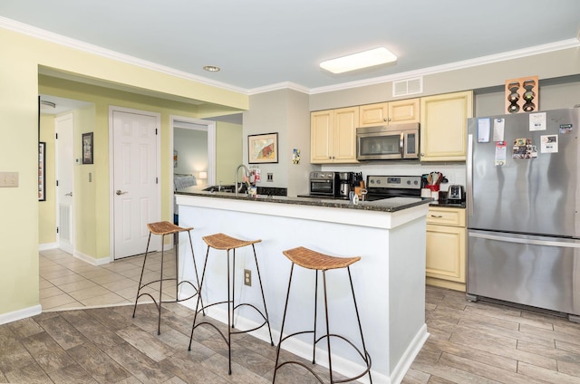 kitchen with stainless steel appliances, a kitchen bar, light wood-style floors, and visible vents