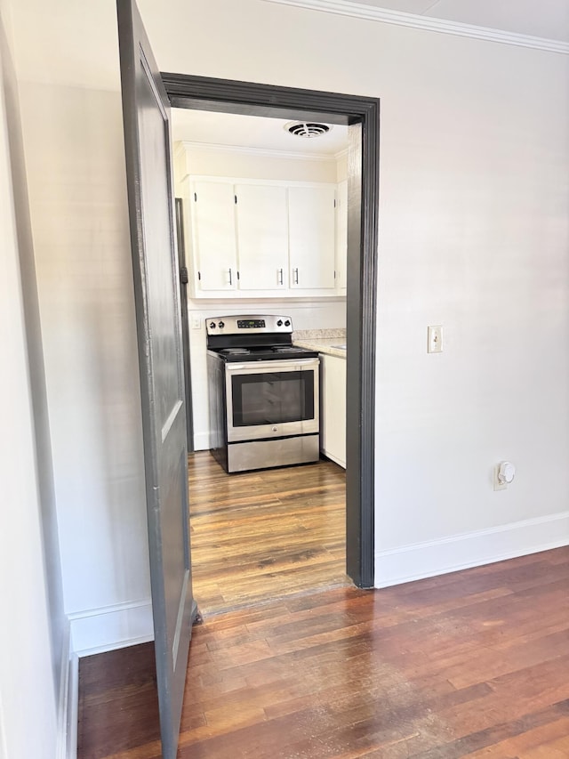 kitchen with white cabinets, stainless steel electric range oven, dark wood-type flooring, and crown molding